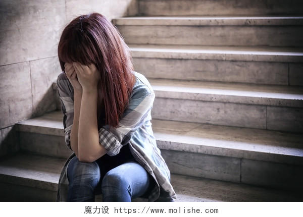 一位女孩坐在楼梯上用双手捂着脸部女人孤独焦虑烦躁恼火烦躁无奈后悔
